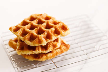 Croffle or Croisant waffle dessert, a marriage between a croissant and a waffle iron. Fresh baked croffle on a white plate. closeup.の写真素材