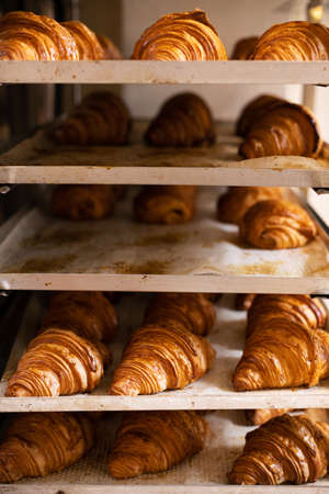 freshly baked crispy golden croissants on a metal trayの写真素材