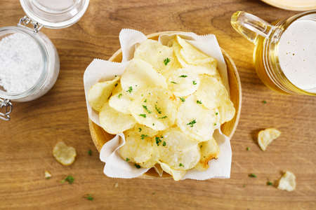 Fresh homemade potato chips with parsley in wooden bowl. Closeup.の写真素材