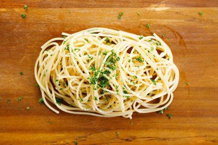 cooked spaghetti pasta with olive oil and chopped parsley on wooden plate. top view.の写真素材