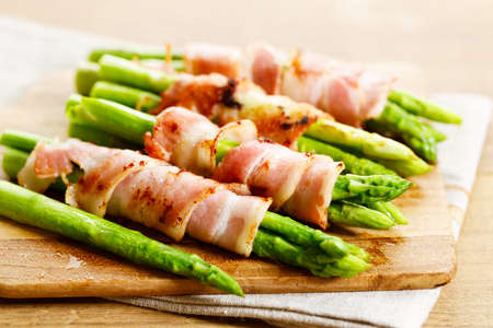 Grilled green asparagus with bacon on wooden plate. Closeup.の写真素材