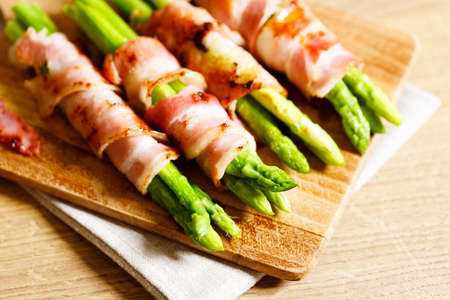 Grilled green asparagus with bacon on wooden plate. Closeup.の写真素材