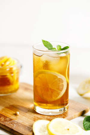 ice tea with sliced lemon and mint leaves in a glass on white wooden table background.の写真素材
