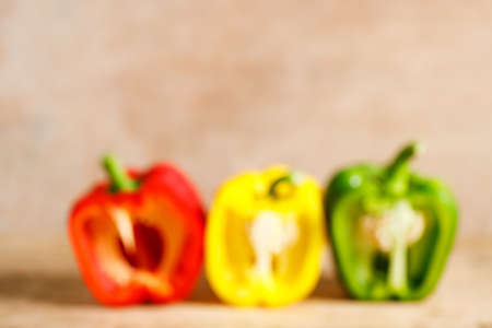 Three sweet red, yellow, green bell peppers on wooden background. Colorful fresh vegetable concept....