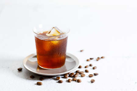 Glass of iced coffee, Iced Americano coffee, with coffee beans on white marble table.の写真素材