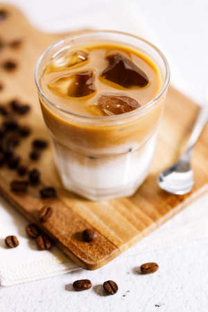 Glass of iced coffee with milk, Iced latte coffee, with coffee beans on white marble table.の写真素材