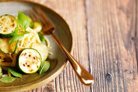 Vegetarian zucchini pasta with roasted zucchini and spaghetti noodles on wooden table. Closeup.の写真素材