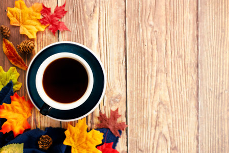Autumn composition with a blue cup of hot tea, dry leaves and blue fabric on wooden table. Top view...