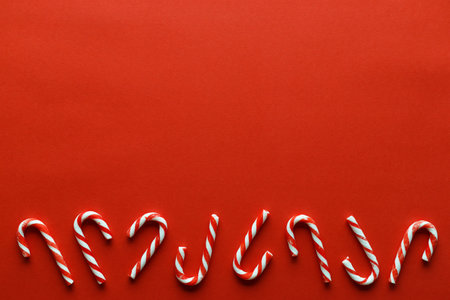 Christmas background with red candy canes on red background. Christmas and New Year background with...