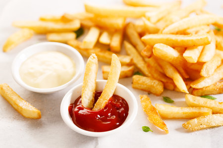 Potato fries with mayo and ketchup on wooden table.の写真素材