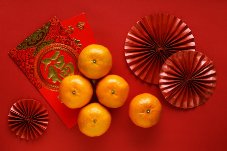 Chinese new year festival decoration with red bags, oranges and red Chinese folded fans on red background. Celebrate Happy Chinese new year background concept. Top view.の写真素材