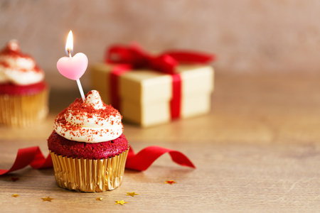 red velvet cupcake top with white cream cheese frosting with candle on wooden table background.の写真素材