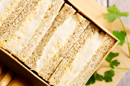 Egg sandwich, Egg salad with mayonnaise between slices of white bread, on wooden board. Closeup.の写真素材