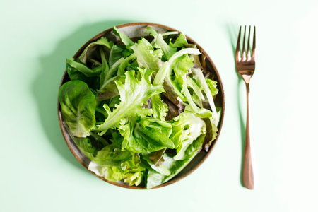 Healthy vegetable salad from mixed green leaves on green background. Closeup.の写真素材