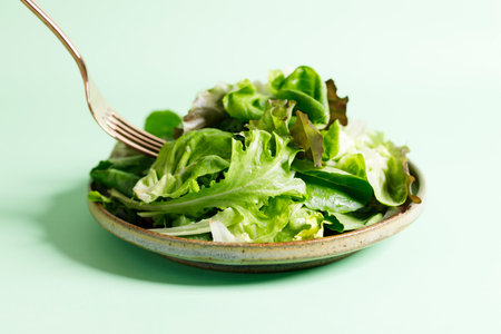 Healthy vegetable salad from mixed green leaves on green background. Closeup.の写真素材