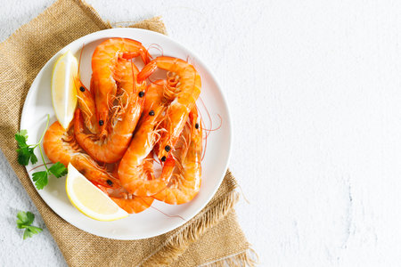 Steamed shrimps with herbs and sliced lemon on white plate. Seafood dish.の写真素材