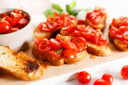 Delicious savory Italian tomato bruschetta slices on white wooden board. Tomato bruschetta with chopped tomatoes, garlic and herbs on toasted bread.の写真素材