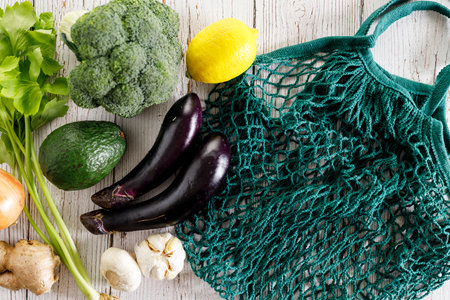 Fresh vegetables in reusable grocery net bag. Broccoli, avocado, eggplant, lemon and herbs in eco cotton bag. Zero waste, plastic-free and sustainable lifestyle.の写真素材