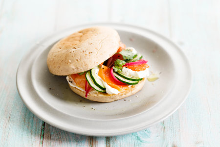 Delicious sandwich with smoked salmon, cream cheese, pickled onions and cucumber slices on wooden table background.の写真素材
