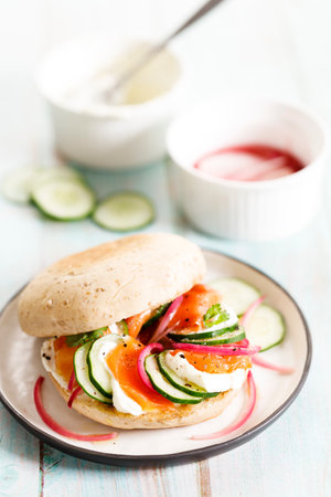 Delicious sandwich with smoked salmon, cream cheese, pickled onions and cucumber slices on wooden table background.の写真素材