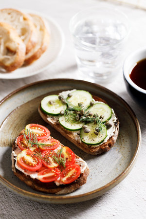 Toasted sliced breads with cream cheese topped with fresh cucumber and cherry tomato. Healthy fresh vegetable toast for breakfast.の写真素材