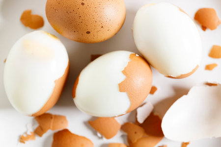 Hard boiled eggs with brown shall on white plate. Closeup.