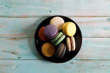 Colorful macaron cookies on black color plate. Sweet French macarons in different colors. Closeup.の写真素材