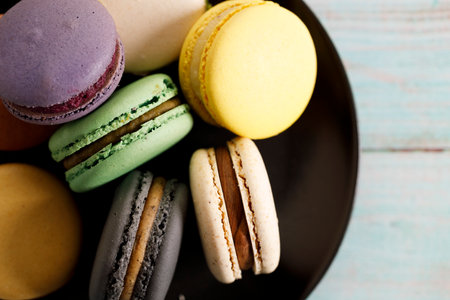 Colorful macaron cookies on black color plate. Sweet French macarons in different colors. Closeup.の写真素材