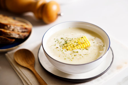 Creamy corn soup in white bowl on white table background.