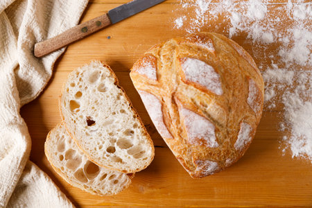 Fresh sourdough bread with a golden crust on wooden table. Top view.