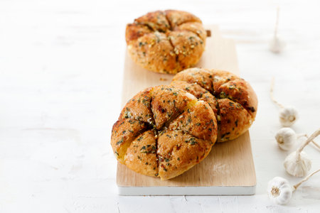 Korean garlic and cheese bread. Bread bun filled with cream cheese, garlic and sugar on white wooden table.の写真素材