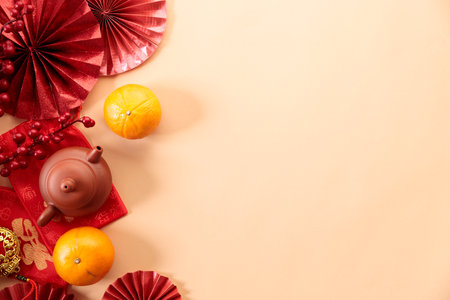 Chinese new year festival decorations with tangerines, classic clay teapot and red Chinese folded fans on soft orange color background. Celebrate Happy Chinese new year background concept. Top view.の写真素材