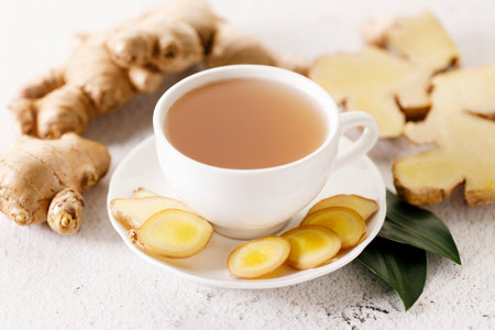 Cup of hot ginger tea with ginger root and slices on white marble background.の写真素材