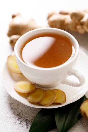 Cup of hot ginger tea with ginger root and slices on white marble background.の写真素材