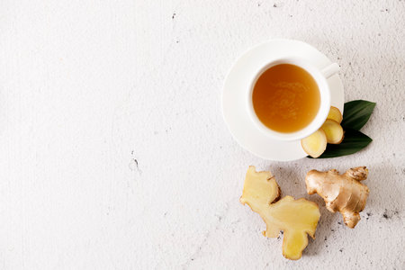 Cup of hot ginger tea with ginger root and slices on white marble background. Top view.の写真素材