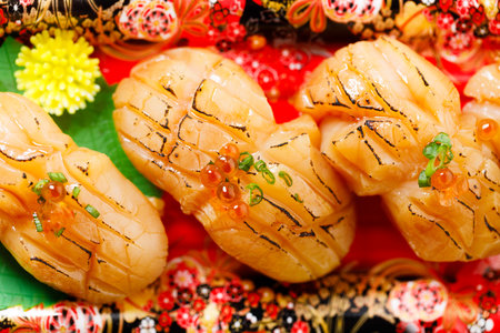 Scallop hotate sushi with sauce on a plastic tray, closeup.の写真素材