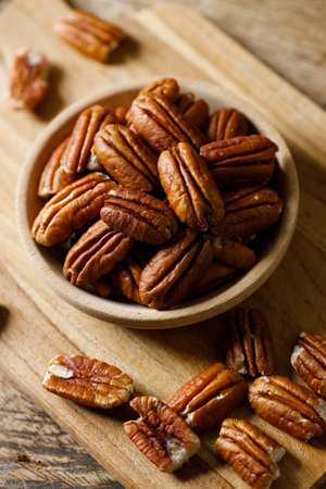 Pecan nuts on rustic wooden table in a wooden bowl. Closeup.の写真素材