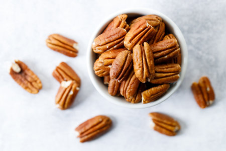 Pecan nuts on white marble table in a white bowl. Closeup.