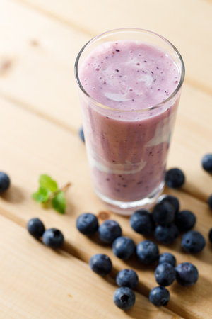 Blueberry smoothie with yogurt in a glass and fresh blueberries on wooden table background.の写真素材