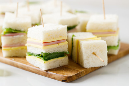 Sandwich of white soft bread with ham, cheese and fresh lettuce, 
square cut, three layers sandwich bread.の写真素材