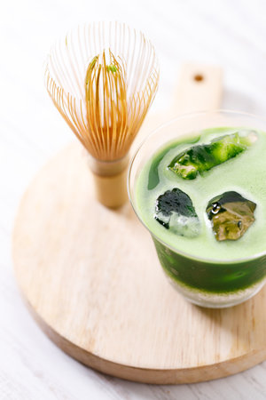 Refreshing matcha drink with pink coconut water presented in multiple layers with rock ice. Green...
