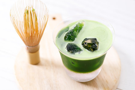 Refreshing matcha drink with pink coconut water presented in multiple layers with rock ice. Green...