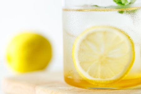 Refreshing lemonade drink with ice, sliced lemon and mint. Cold lemonade on white wooden table background.の写真素材