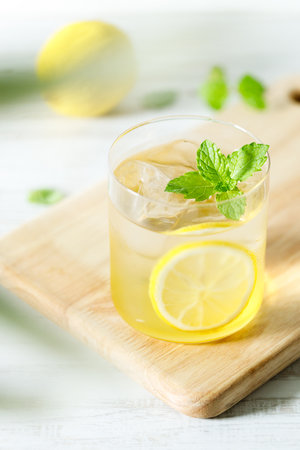 Refreshing lemonade drink with ice, sliced lemon and mint. Cold lemonade on white wooden table background.の写真素材