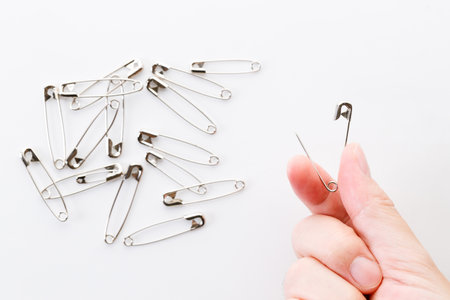 Hand holding safety pin over white background.の写真素材