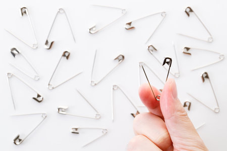 Hand holding safety pin over white background.の写真素材