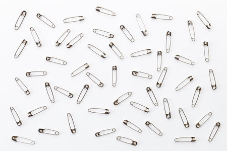 Silver safety pins scattered on white background. Closeup.の写真素材