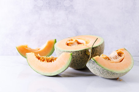 Slices of fresh sweet cantaloupe melon, orange melon, on white marble background.