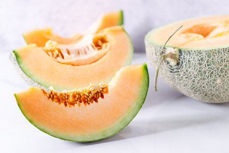 Slices of fresh sweet cantaloupe melon, orange melon, on white marble background.の写真素材