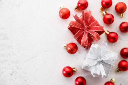 Red and white gift boxes tied with bows on white marble background. Christmas decorations and red balls on white background. Christmas New year concept. Top view.の写真素材